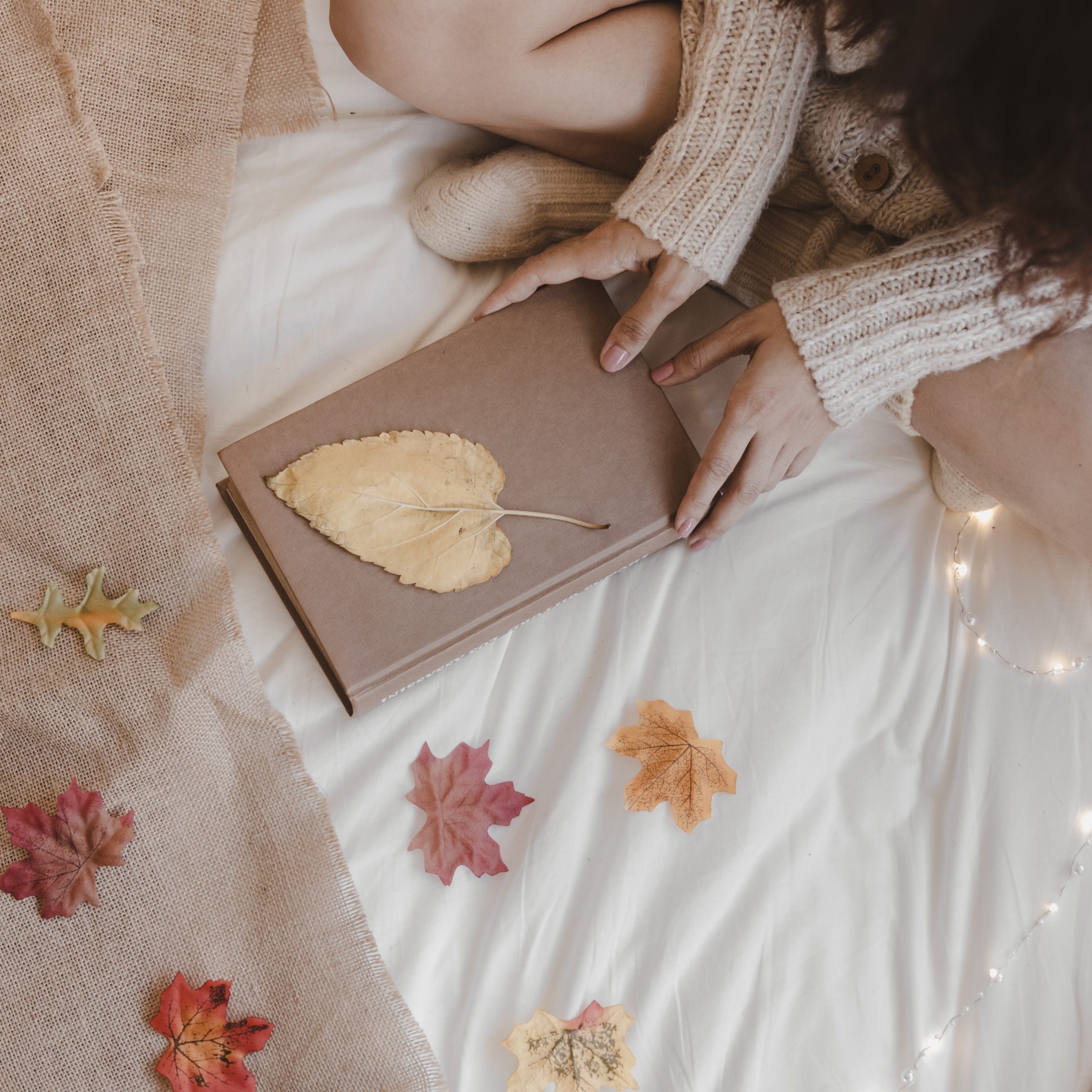 crop-woman-with-book-near-autumn-leaves